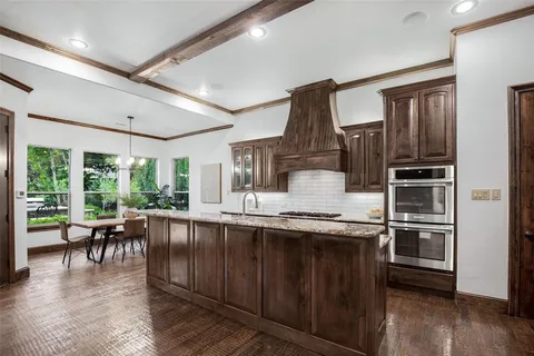 a kitchen with kitchen island granite countertop a large window and stainless steel appliances