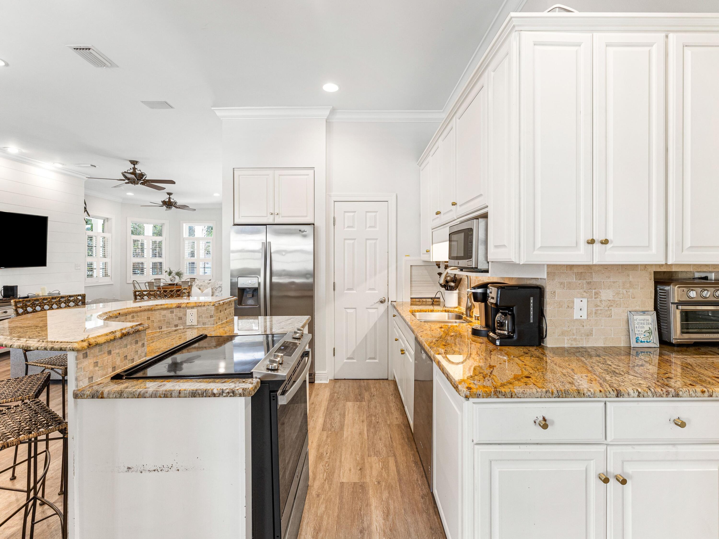 41 Winston Lane Inlet Beach, FL 32461 - Photo 25 of 50 a kitchen with stainless steel appliances granite countertop a stove top oven a sink a dining table and chairs with white cabinets