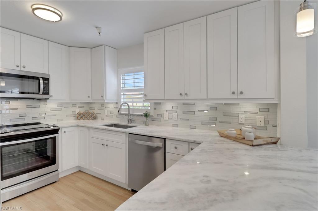 4430 Botanical Pl Circle, Unit 101 Naples, FL 34112 - Photo 3 of 18 a kitchen with stainless steel appliances granite countertop a stove a sink and a microwave