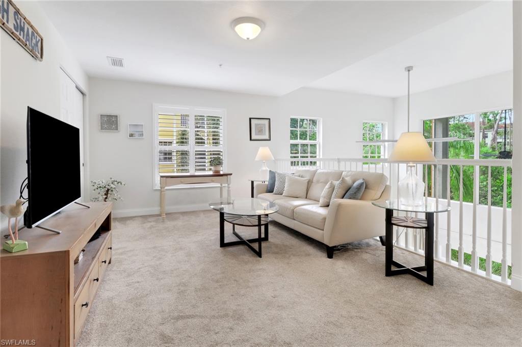 4430 Botanical Pl Circle, Unit 101 Naples, FL 34112 - Photo 8 of 18 a living room with furniture and a flat screen tv