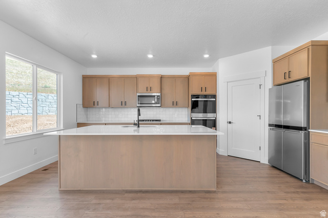 1341 West 2350 South, Unit 10 Perry, UT 84302 - Photo 6 of 18 Kitchen featuring a large central island with a white countertop, wood-finish cabinetry, stainless steel appliances, and wood-finish flooring