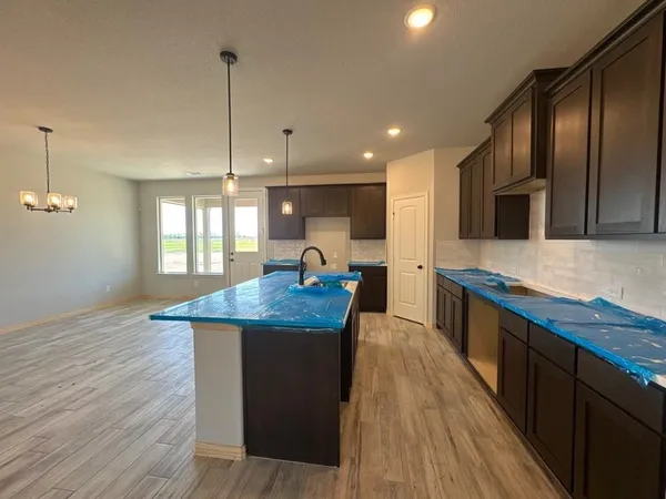 a kitchen with kitchen island granite countertop wooden floors and wide window