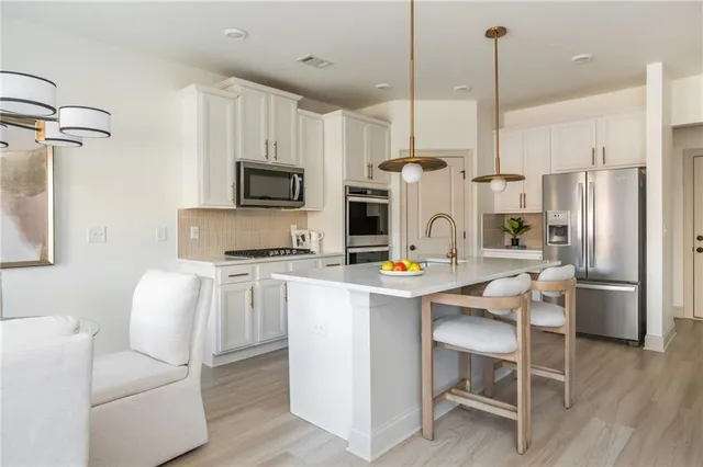 a kitchen with a refrigerator a stove top oven a sink dishwasher and white cabinets