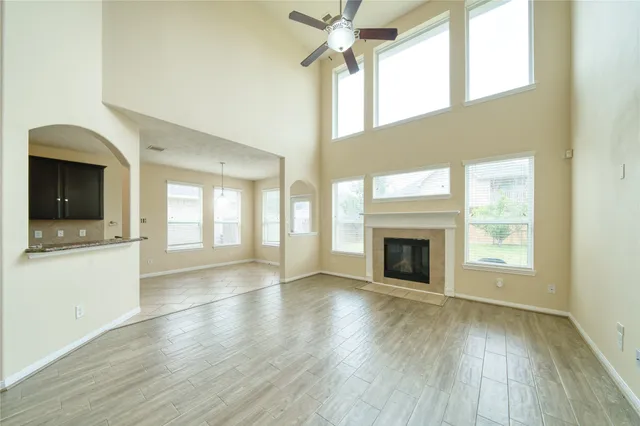 a view of an empty room with wooden floor fireplace and a window