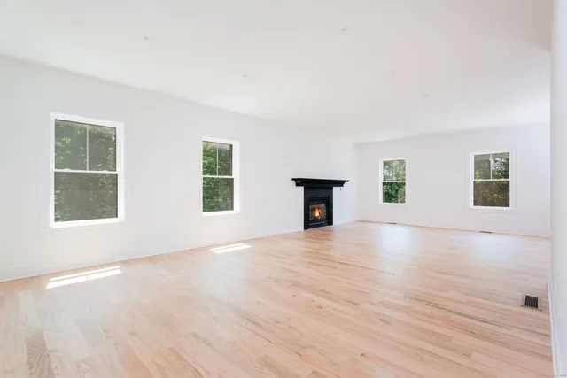 an empty room with windows and fireplace