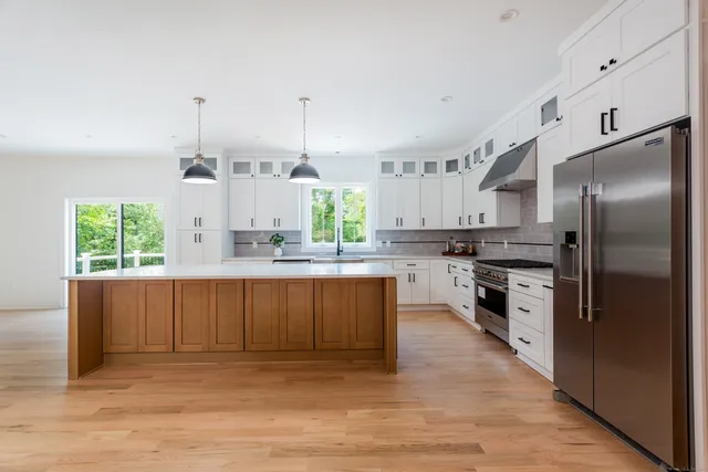 a kitchen with stainless steel appliances kitchen island granite countertop a refrigerator a stove a sink and a wooden floors