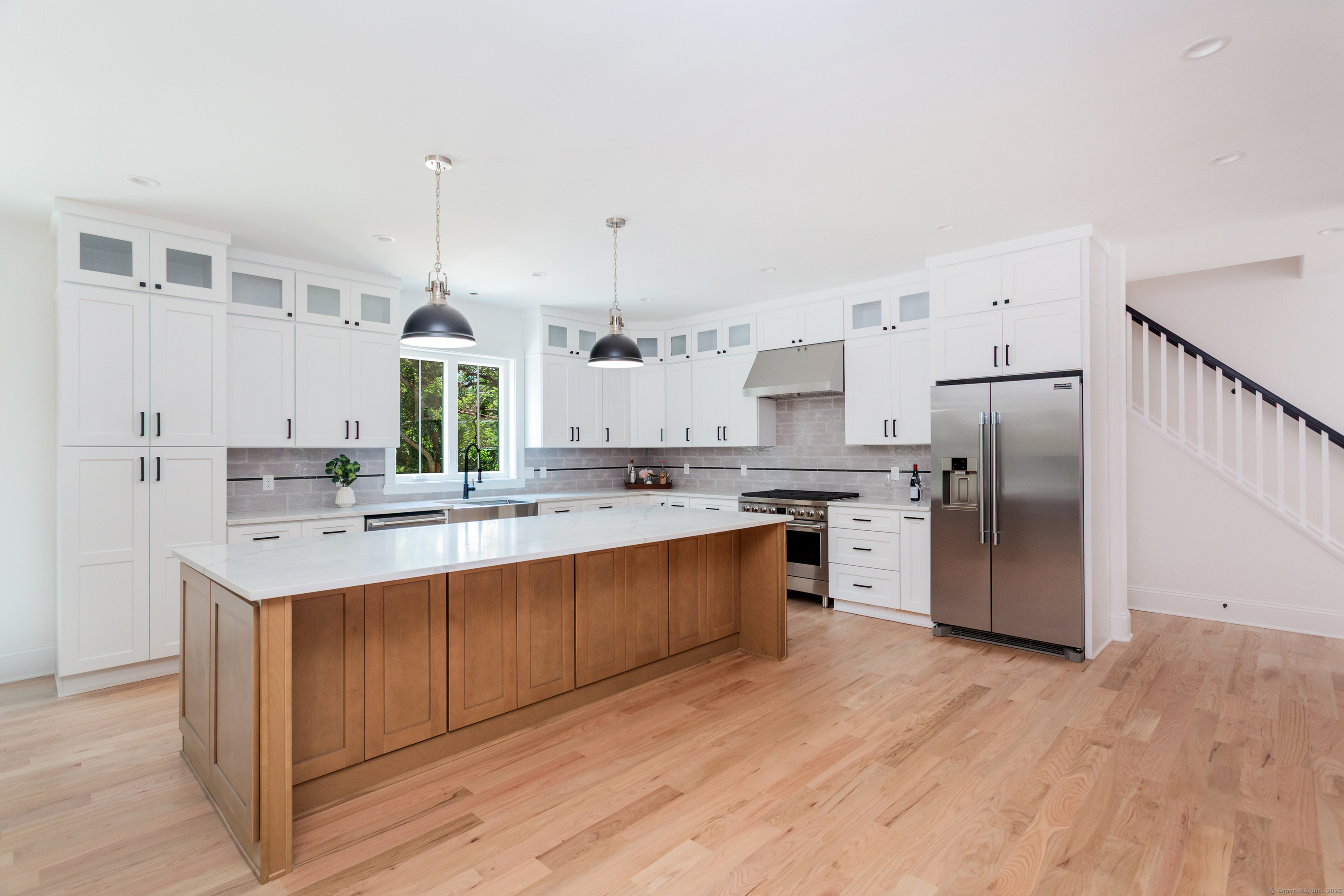 815 James Farm Road Stratford, CT 06614 - Photo 9 of 34 a large kitchen with a center island wooden floor stainless steel appliances and windows