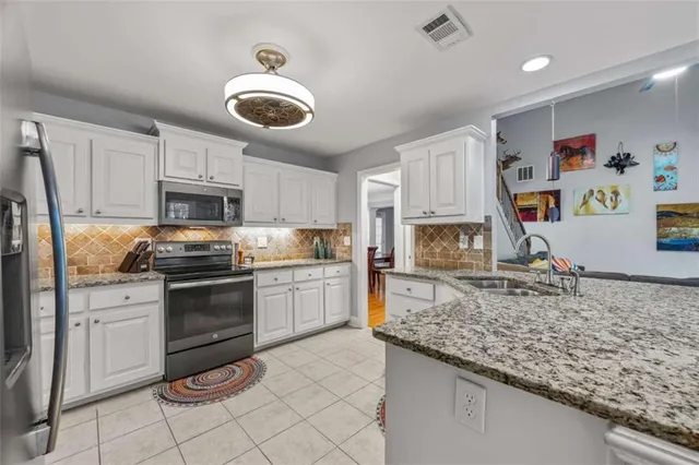a kitchen with kitchen island granite countertop stainless steel appliances and white cabinets