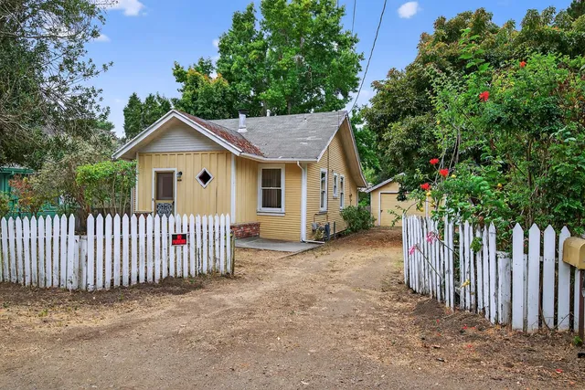 a view of a house with a small yard and wooden fence