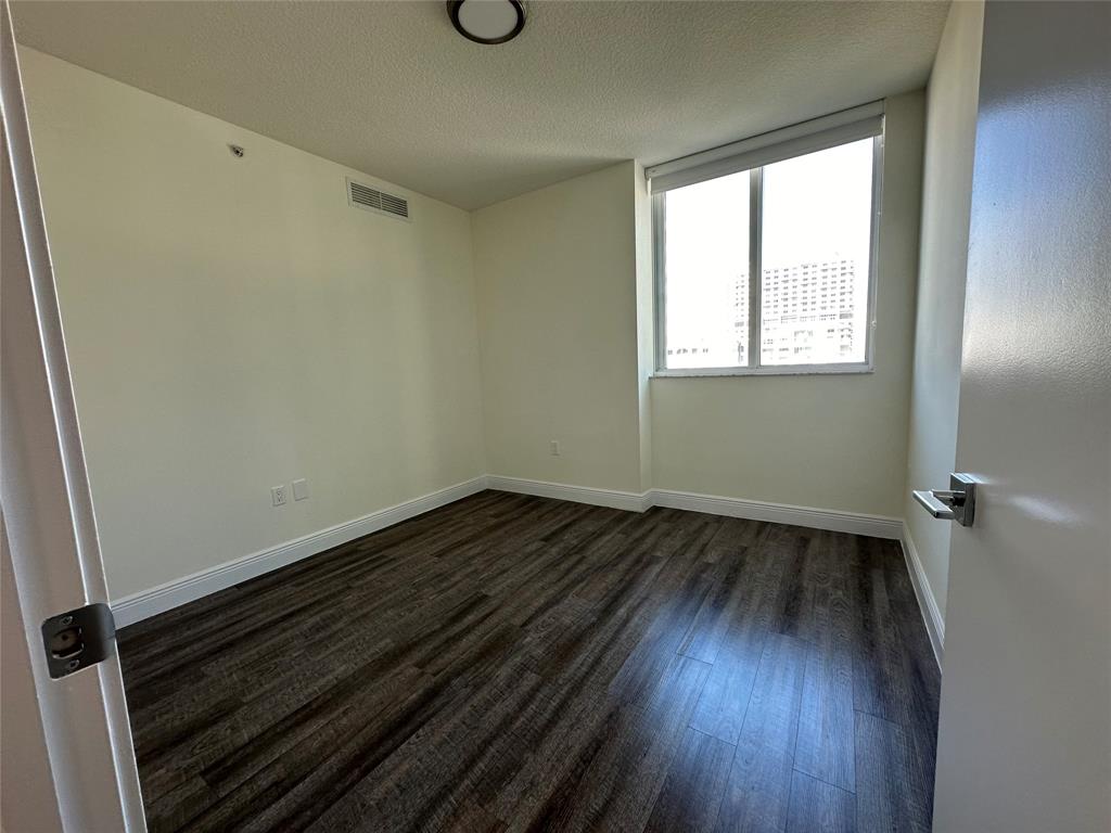110 Southwest 12th Street, Unit 902 Miami, FL 33130 - Photo 11 of 25 a view of an empty room with wooden floor and a window