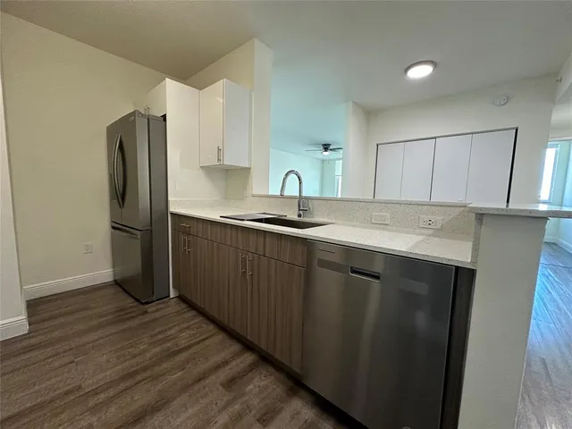 a kitchen with a sink a refrigerator and cabinets