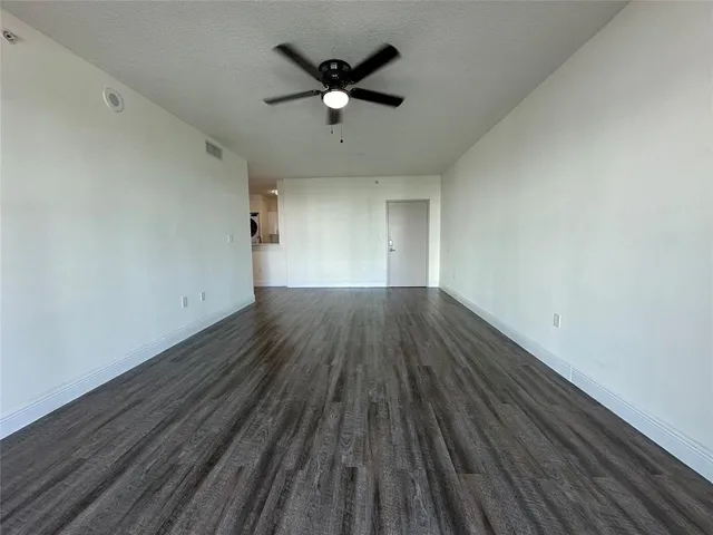 an empty room with wooden floor and a ceiling fan