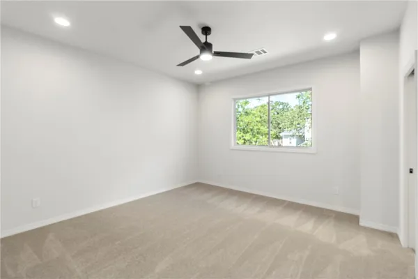 an empty room with windows and ceiling fan