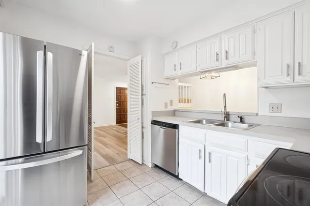 a kitchen with stainless steel appliances granite countertop a refrigerator sink and white cabinets