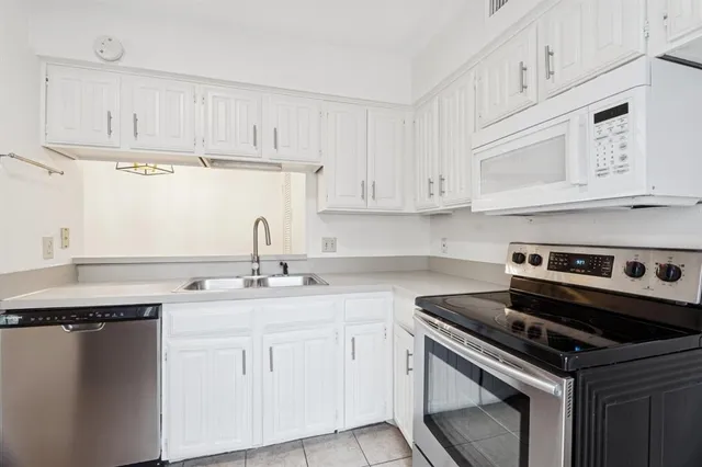 a kitchen with white cabinets and appliances