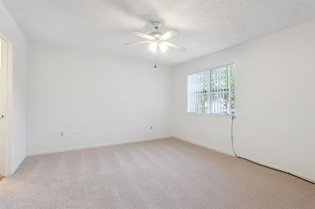 an empty room with a window and a ceiling fan