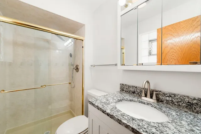 a bathroom with a granite countertop sink toilet and shower