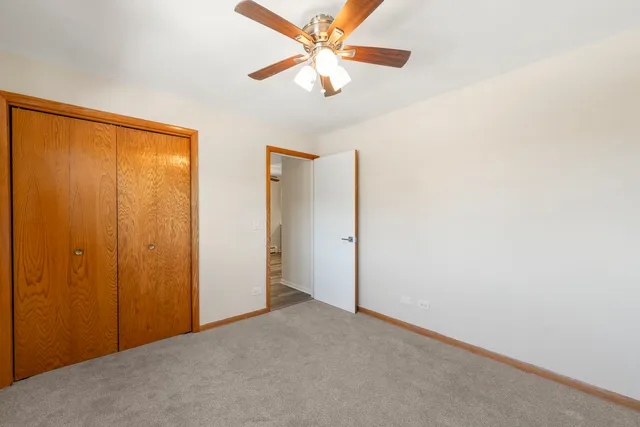 an empty room with closet and a ceiling fan