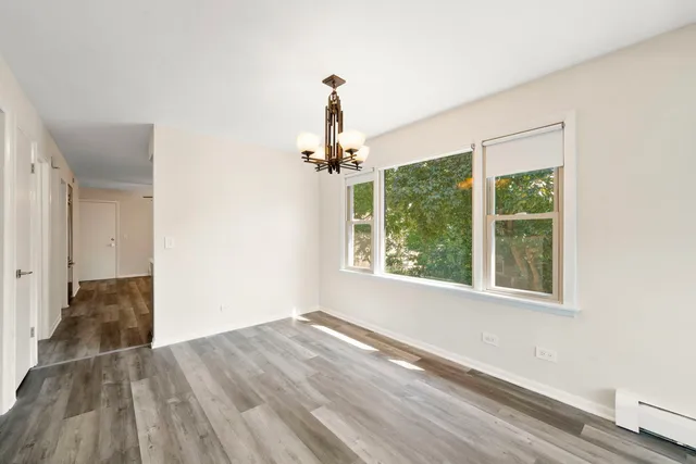 a view of a room with wooden floor chandeliers and kitchen view