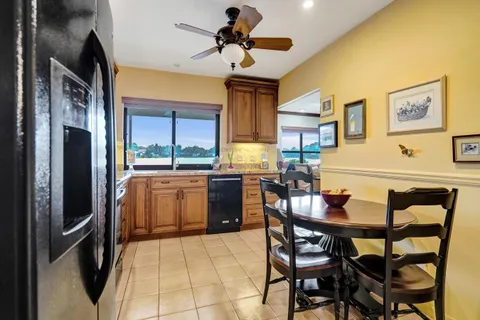 a kitchen with stainless steel appliances granite countertop a dining table chairs refrigerator and sink