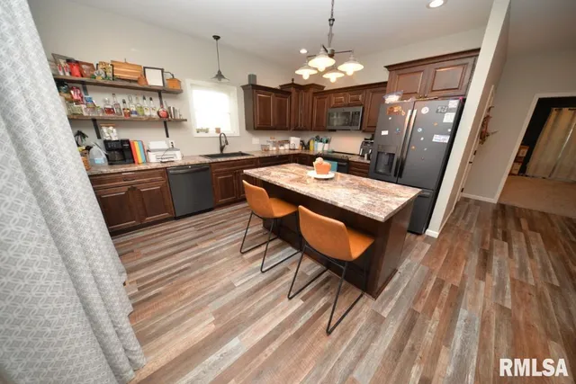 a kitchen with stainless steel appliances granite countertop a refrigerator a sink dishwasher a stove and white countertops with wooden floor