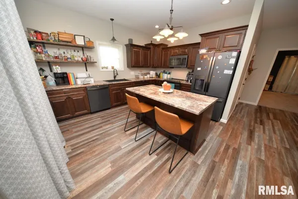 a kitchen with stainless steel appliances granite countertop a refrigerator a sink dishwasher a stove and white countertops with wooden floor