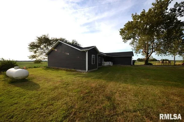 a backyard of a house with large trees and a wooden fence