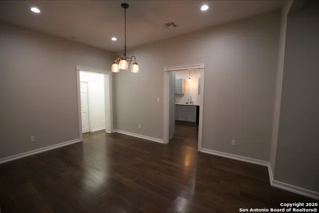 an empty room with wooden floor and chandelier fan