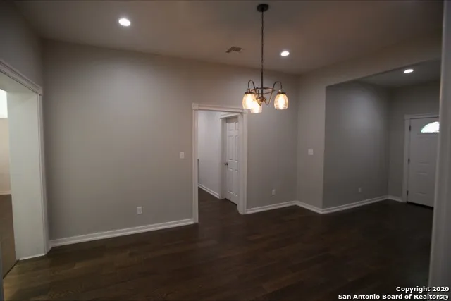 an empty room with wooden floor fan and window