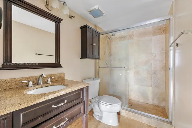 a bathroom with a granite countertop sink toilet and shower