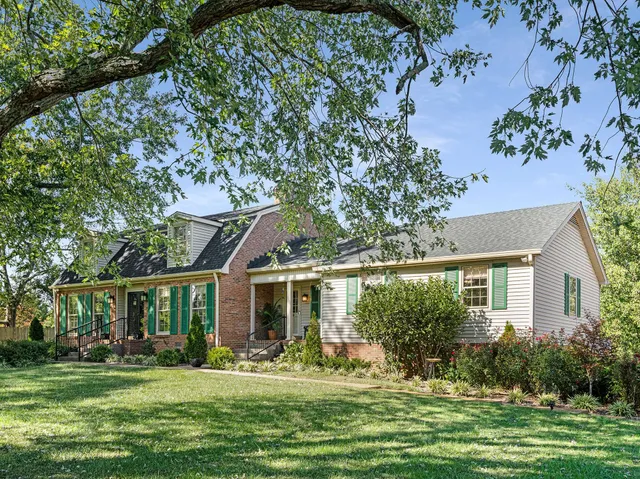 front view of a brick house with a large window and potted plants