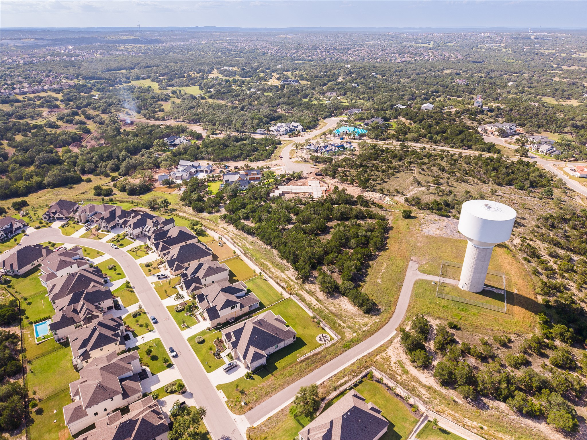 320 Old Stone Road Austin, TX 78737 - Photo 39 of 40 An aerial perspective reveals a vibrant neighborhood nestled among green hills, with a prominent water tower standing guard.