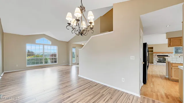 a view of a livingroom with a chandelier wooden floor and a kitchen