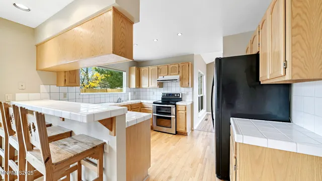 a kitchen with stainless steel appliances granite countertop a refrigerator a sink dishwasher a stove and white cabinets with wooden floor