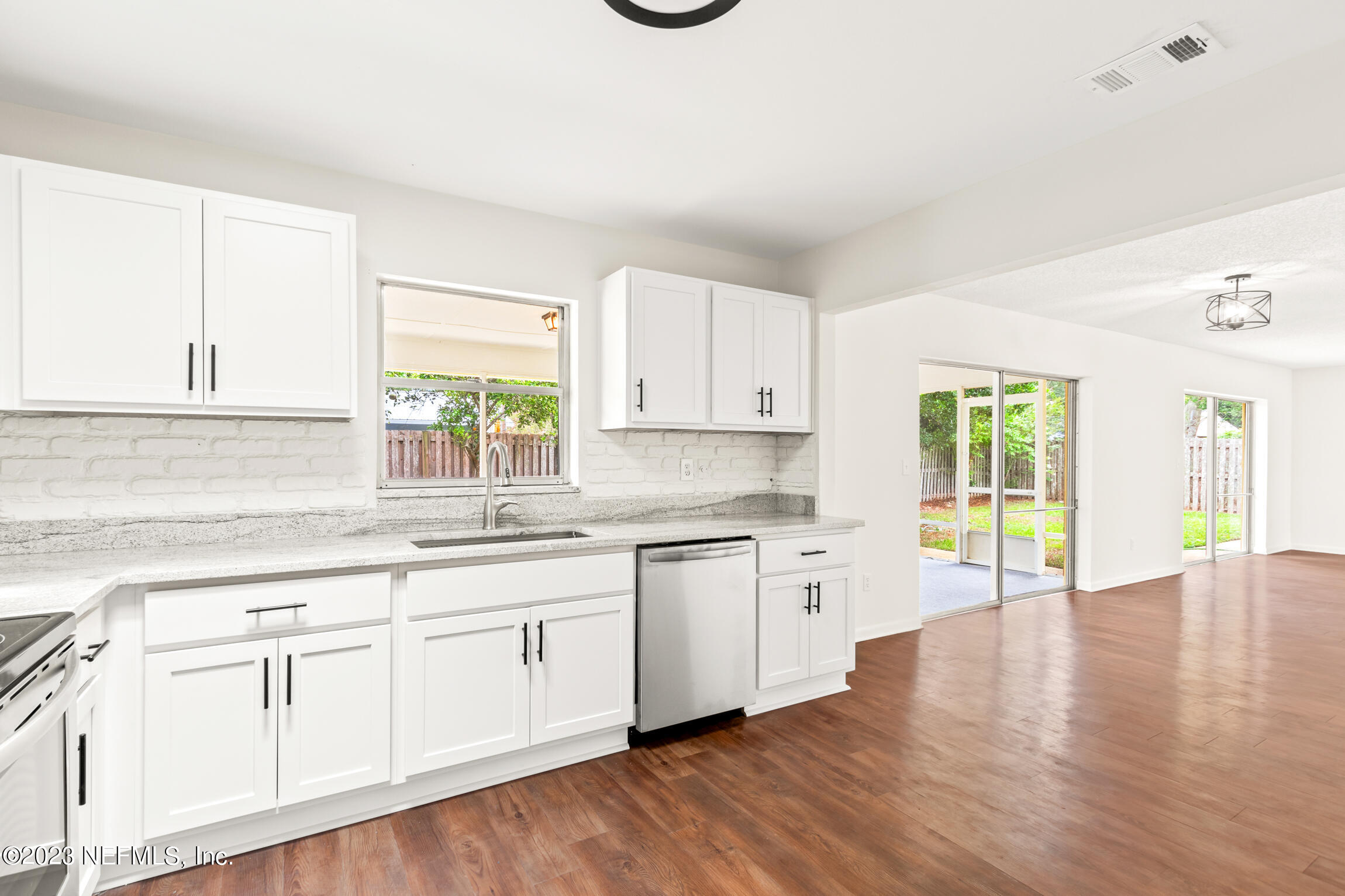 968 Espinado Avenue St. Augustine, FL 32086 - Photo 10 of 41 a open kitchen with granite countertop a stove a sink and white cabinets with wooden floor next to windows
