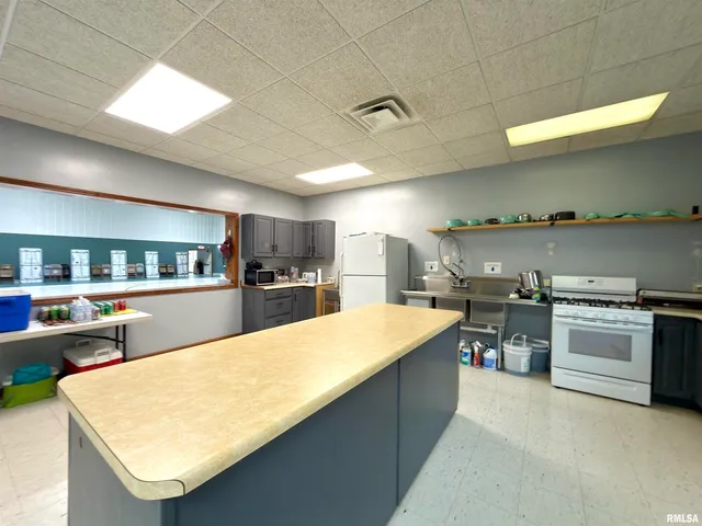 a large kitchen with a large counter top a stove a sink and a refrigerator