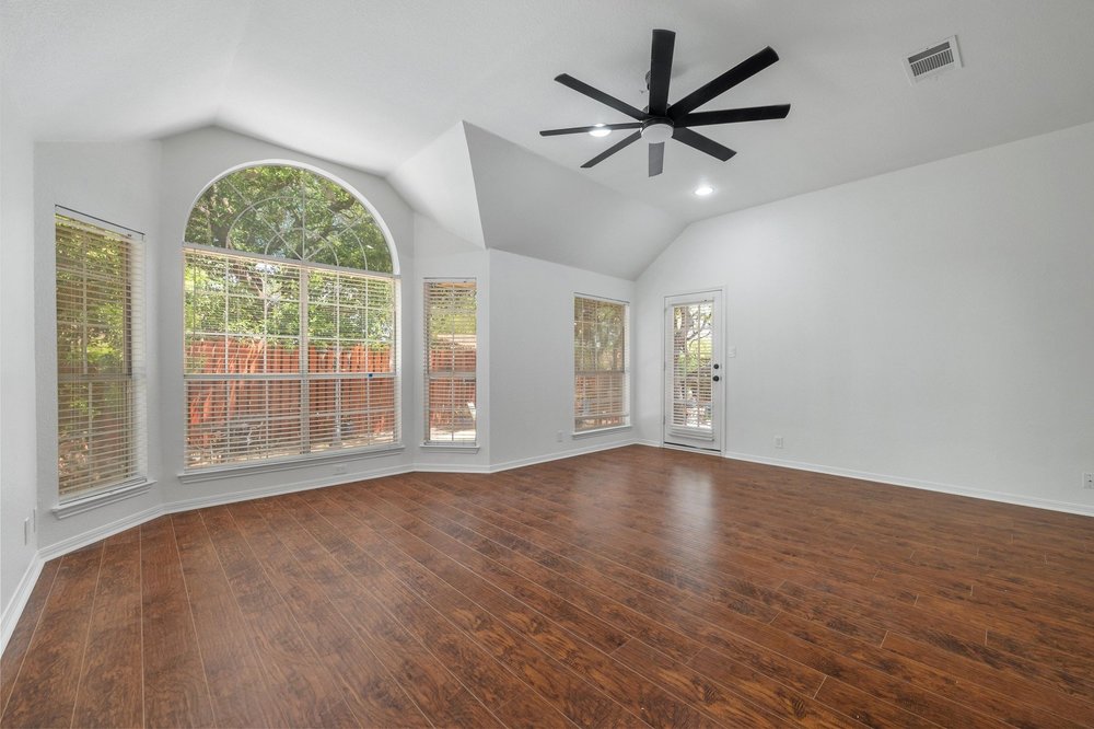 209 El Rio Drive Lakeway, TX 78734 - Photo 22 of 40 an empty room with wooden floor fan and windows
