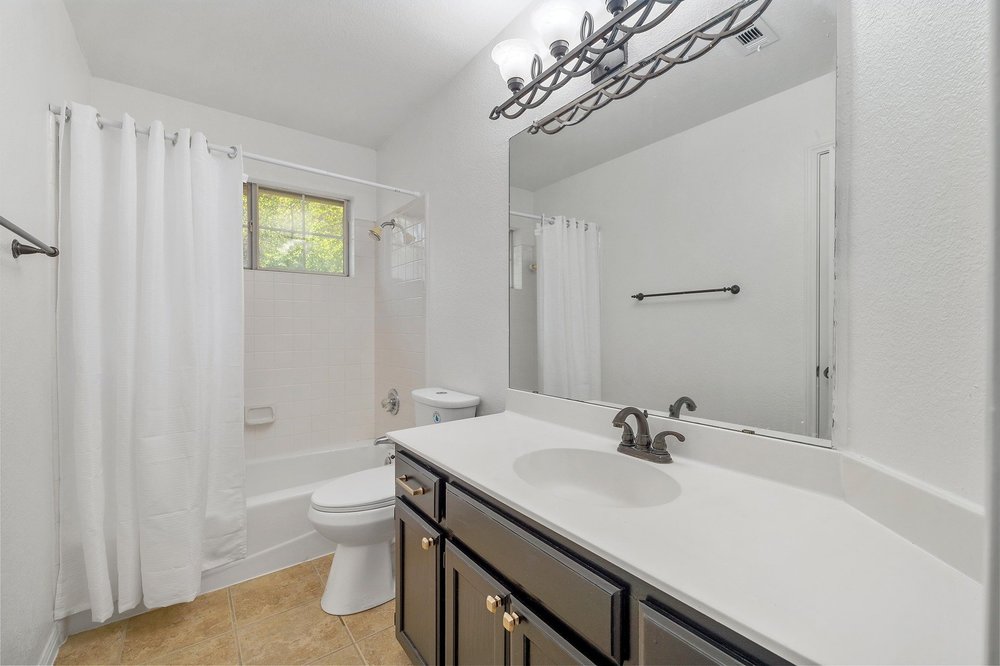 209 El Rio Drive Lakeway, TX 78734 - Photo 29 of 40 a bathroom with a sink a toilet and shower curtain