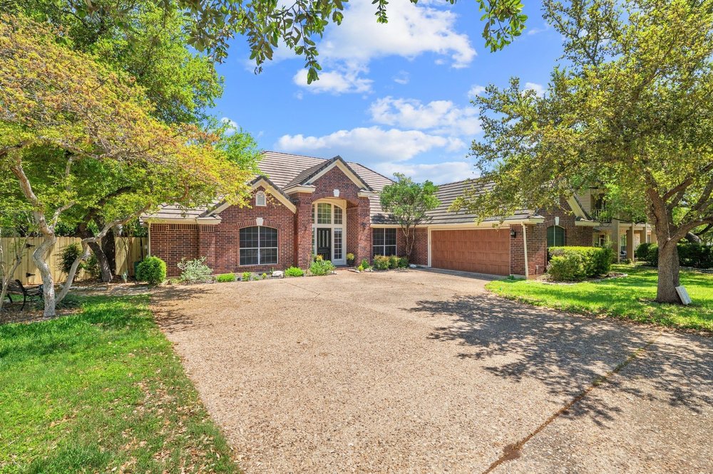 209 El Rio Drive Lakeway, TX 78734 - Photo 7 of 40 a front view of a house with a garden and trees