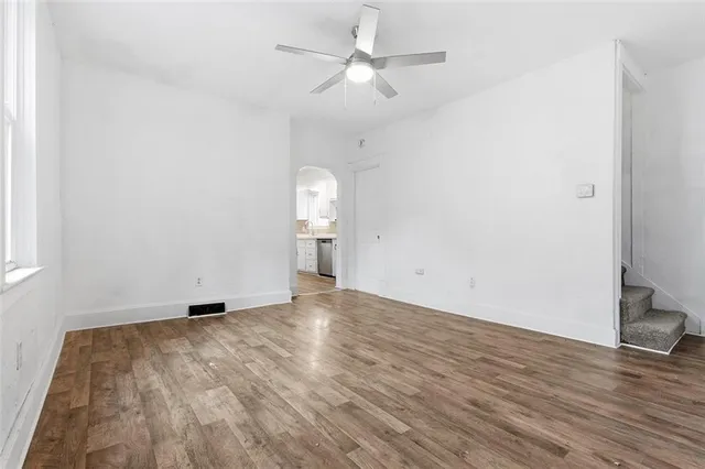 an empty room with wooden floor and fan