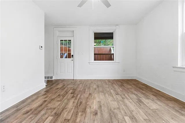 an empty room with wooden floor and windows