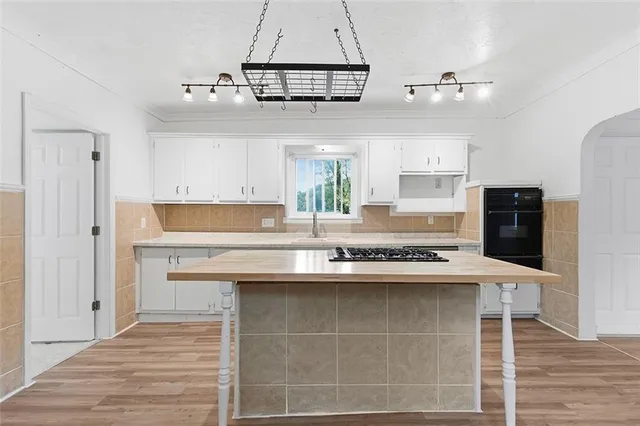 a kitchen with kitchen island granite countertop a sink cabinets a refrigerator and a stove