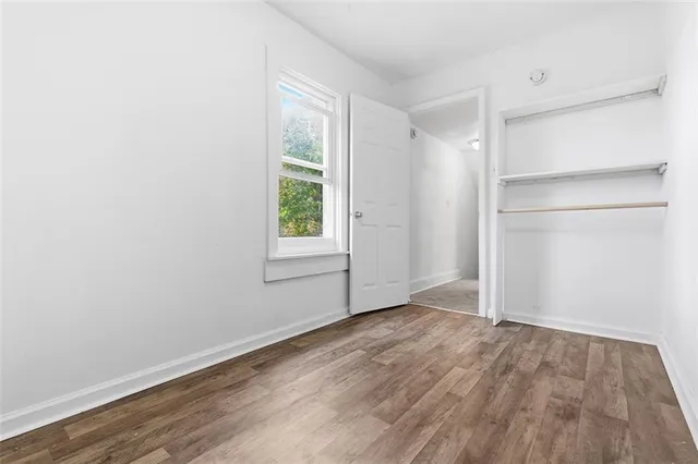 an empty room with wooden floor closet and windows