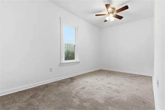 an empty room with a window and a fan