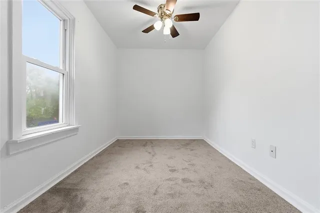 an empty room with a window and a fan