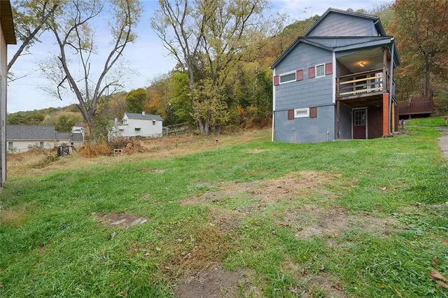 a view of a brick house with a big yard and large trees