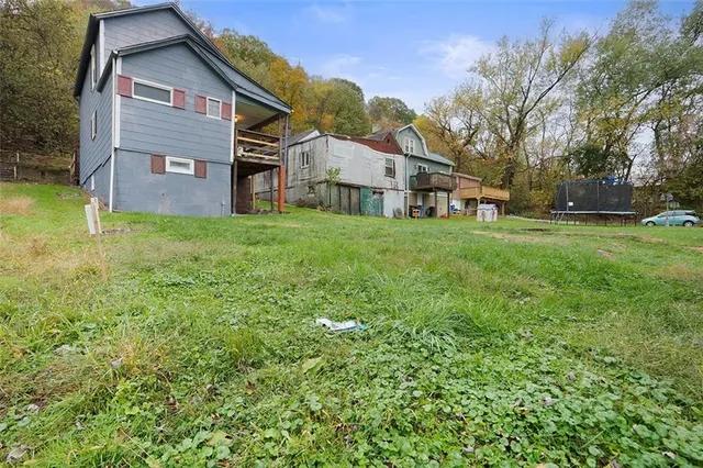 a backyard of a house with plants and large trees