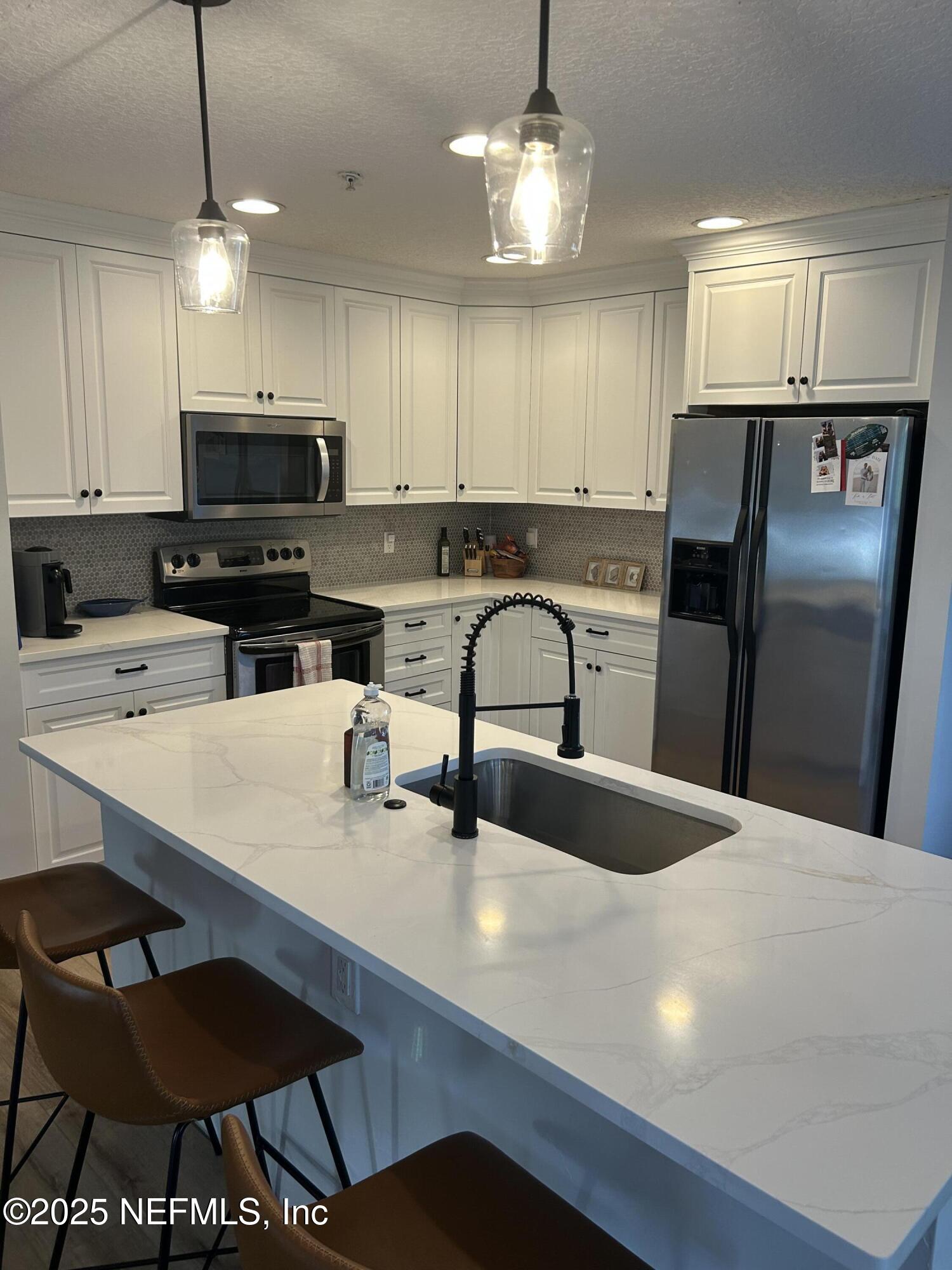 2102 Marsh Point Road, Unit 2102 Neptune Beach, FL 32266 - Photo 5 of 20 a kitchen with stainless steel appliances a refrigerator a stove a sink a dining table and chairs