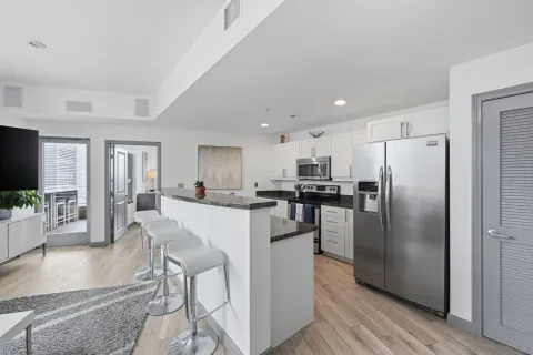 a kitchen with a refrigerator a counter top space a sink cabinets and stainless steel appliances