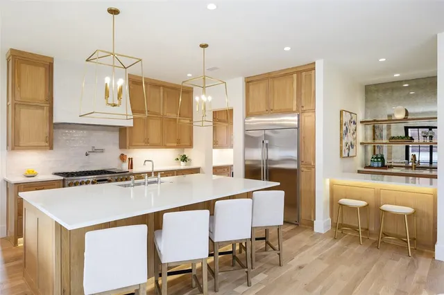 a kitchen with stainless steel appliances granite countertop a stove a sink a refrigerator a dining table and chairs with wooden floor